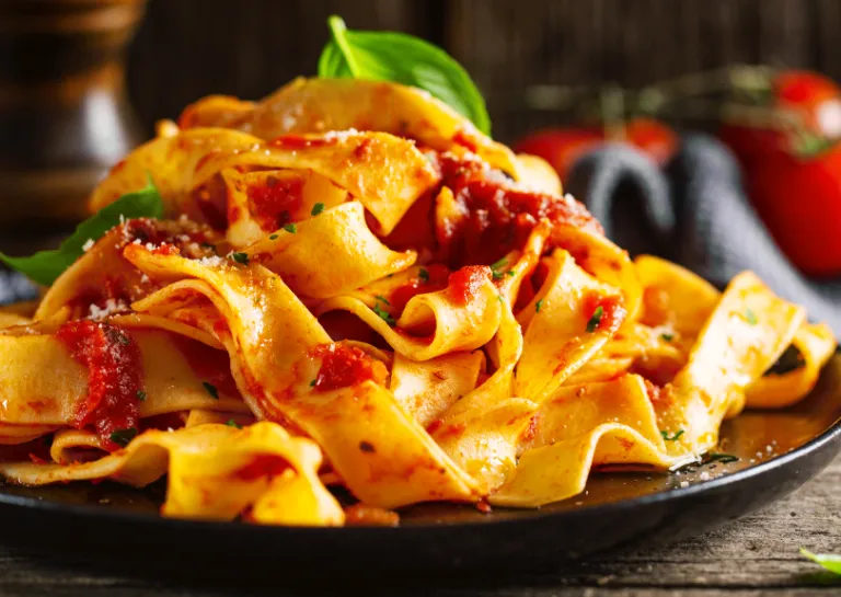 Sauce Bolognese mit Bandnudeln angerichtet auf einem schwarzen Teller