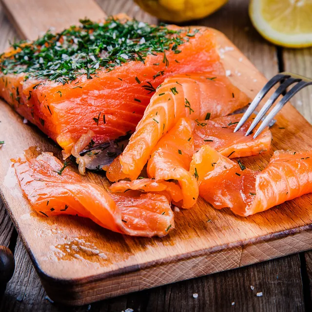 Frischer Lachs mit Dill auf einem Schneidebrett aus Holz.