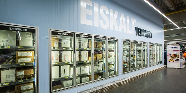 Schränke mit Tiefkühlware, über denen der Schriftzug "Eiskalt verpackt" steht 